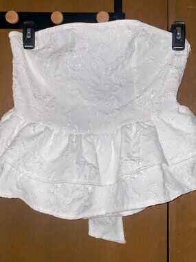 White sleeveless top with embossed white floral pattern and tie closure